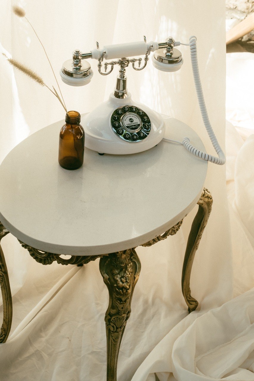 Vintage white rotary phone on wooden side table